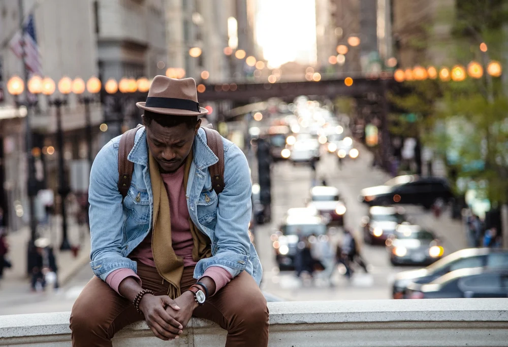 man with hands clasped, looking down, feeling depressed